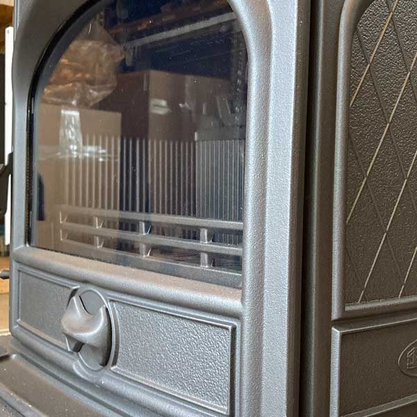 Voorkant met glas en primaire luchtinlaat van een dovre 425GM multifuel. De ronde knop in de deur on der het glas